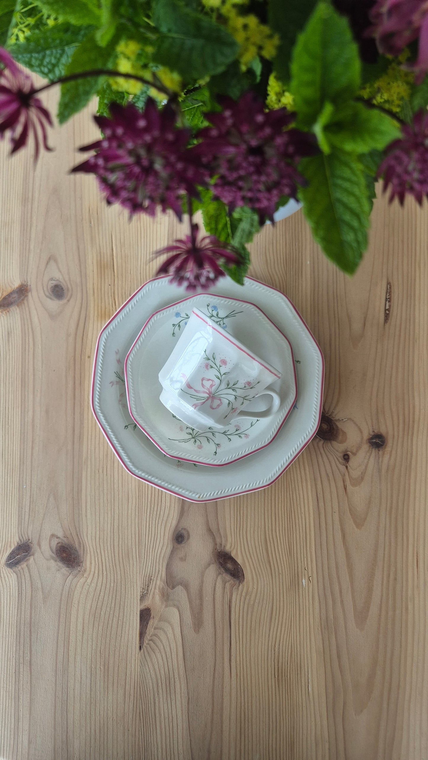 Churchill-porslinsservis med tekanna och kopp, omgivet av lila blommor på träbord